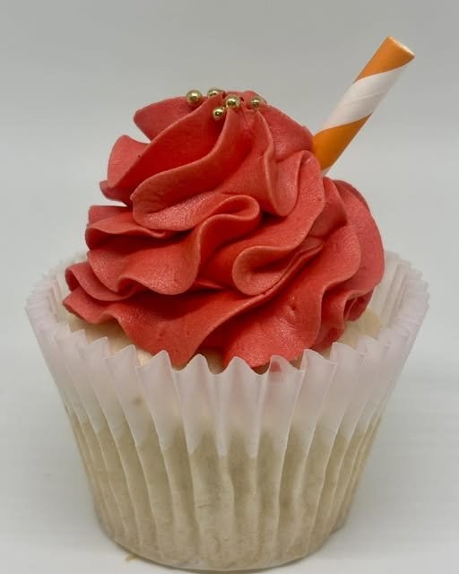 A Cupcake Apothecary cupcake with ruffled red buttercream, gold pearls, and a striped accent
